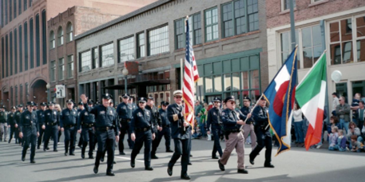Colorado Emerald Society marching, with American flag, in Denver St Patrick's Day Parade.
