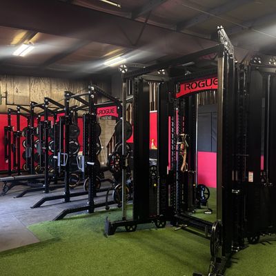 A modern gym with Rogue fitness equipment and green turf flooring.