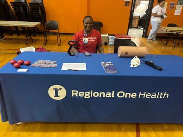 A smiling woman at a Regional One Health informational table indoors.
