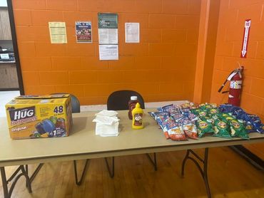 Table with snacks, napkins, and condiments against an orange wall.