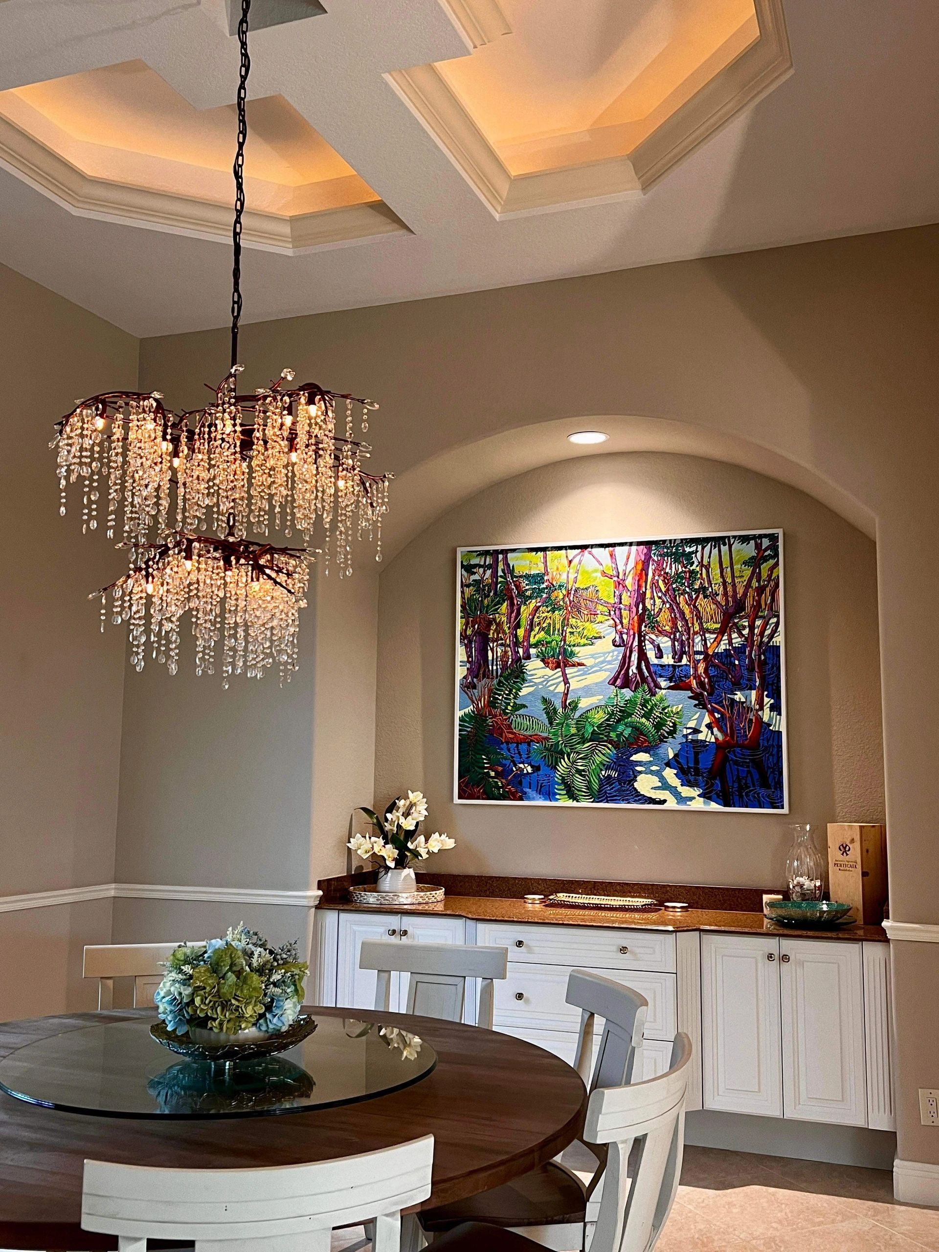 Elegant dining area with a crystal chandelier and colorful wall art.