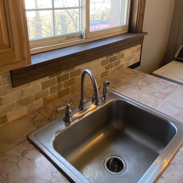 Clean kitchen sink with window above.