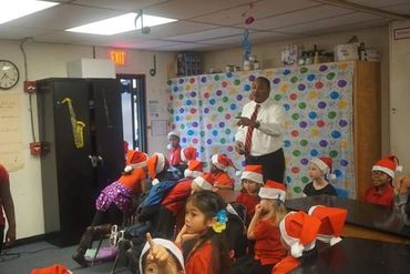 Teacher engaging young students wearing Santa hats in a festive classroom.