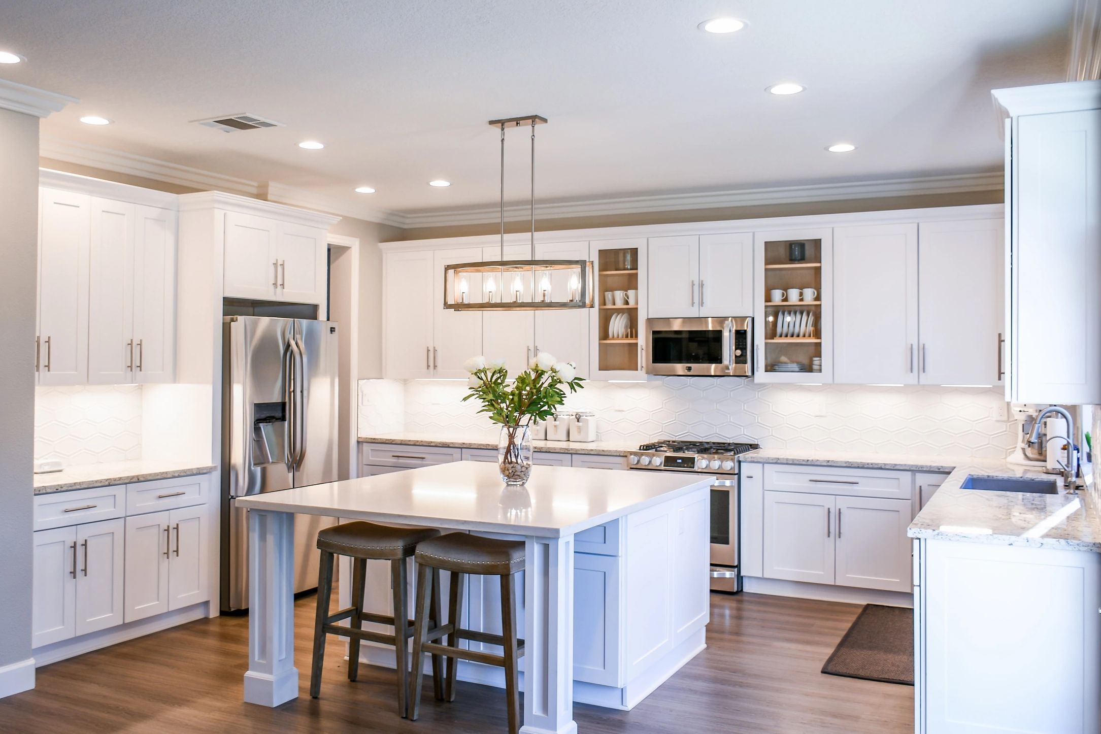 Bright white kitchen with white granite counters and a large center island. 