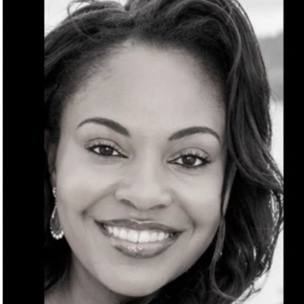 Smiling woman with curly hair in black and white photo.
