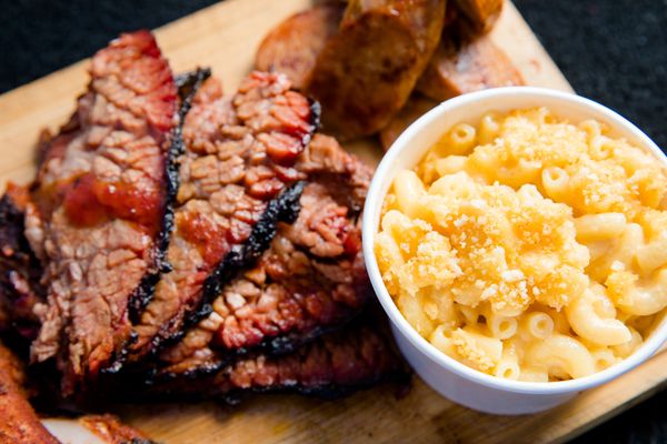 Grilled cooked meat with a bowl of mac and cheese 