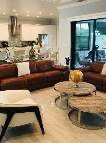 Modern living room with brown leather sofas and round wooden tables.