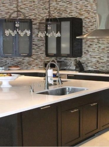 Modern kitchen with dark cabinets and pendant lights.