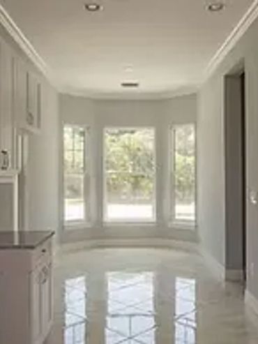 Empty white kitchen with large window and glossy floor.