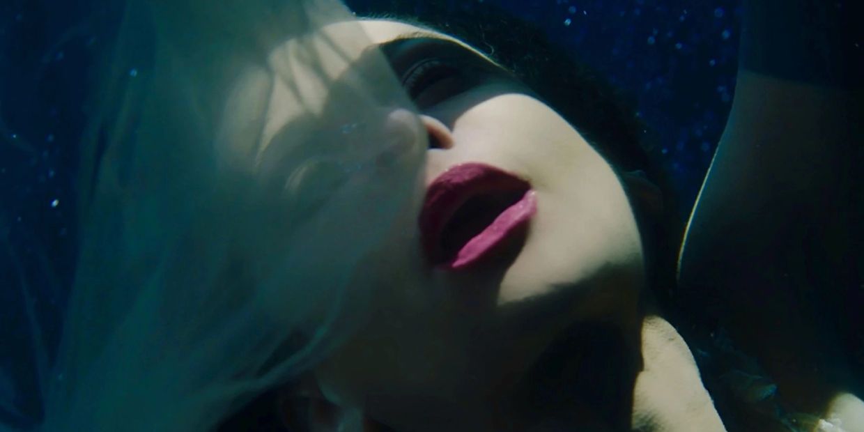 Close-up of a woman's face underwater with flowing hair and dramatic lighting.