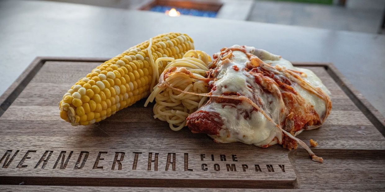 Chicken Parmesan with pasta and corn on a Neanderthal Fire Company Butcher Plate