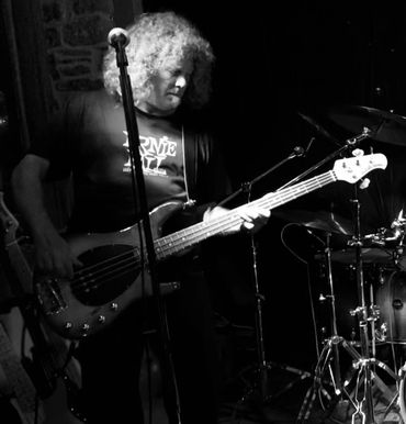 Black and white photo of a musician playing bass guitar on stage.