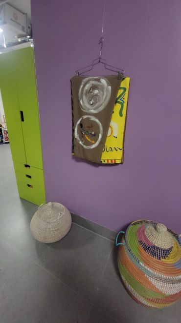 Colorful storage baskets and clothes hanger against purple wall.