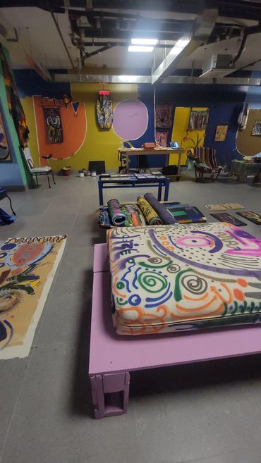 Colorful art studio with paintings and decorated tables.