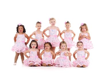 Group of young girls in matching pink dance costumes posing for a photo.