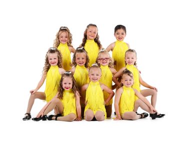 Young girls in yellow dance costumes posing together in a group.