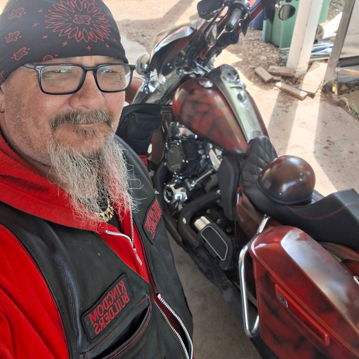 Man with beard and bandana posing with a custom motorcycle.