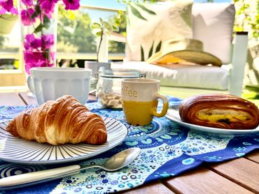 Breakfast setup with croissants, coffee, and a cozy outdoor seating area.