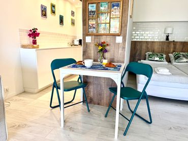 Cozy dining area with a small table, two teal chairs, and fresh flowers.