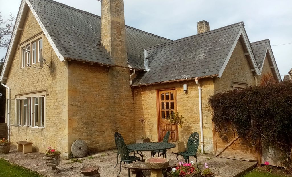 Cozy stone cottage with a slate roof and garden patio.