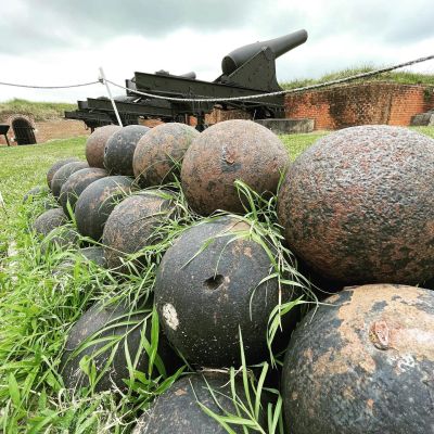 Old cannon with iron cannonballs in front.