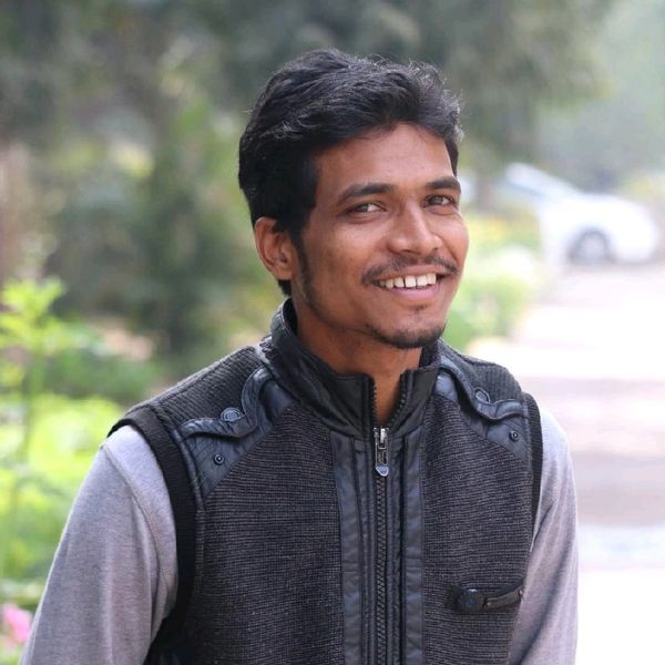 Young man smiling outdoors in casual attire.