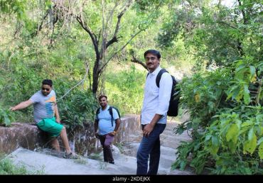 Three men hiking on a forest trail with backpacks.