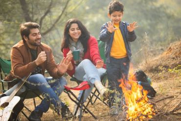 Family enjoying a campfire outdoors with smiles and warmth.