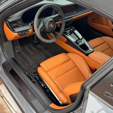 Interior maintenance detailing removing dust and light debris from a luxury vehicle.