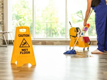 Safety sign with the phrase Caution wet floor and cleaner inside.