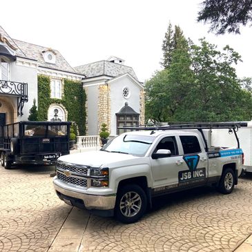 White work truck parked in front of a large house.