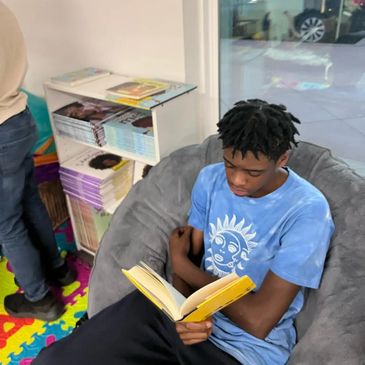 Young man reading a book while sitting on a bean bag chair.