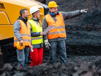 Three construction workers in safety gear discussing something in the distance.