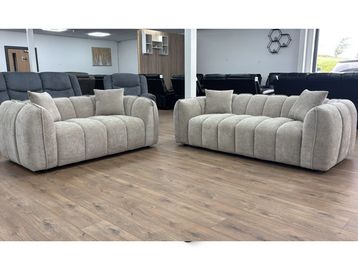 Two plush beige sofas with rounded designs in a showroom.