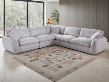 Modern gray sectional sofa in a spacious living room with large windows and a patterned area rug.