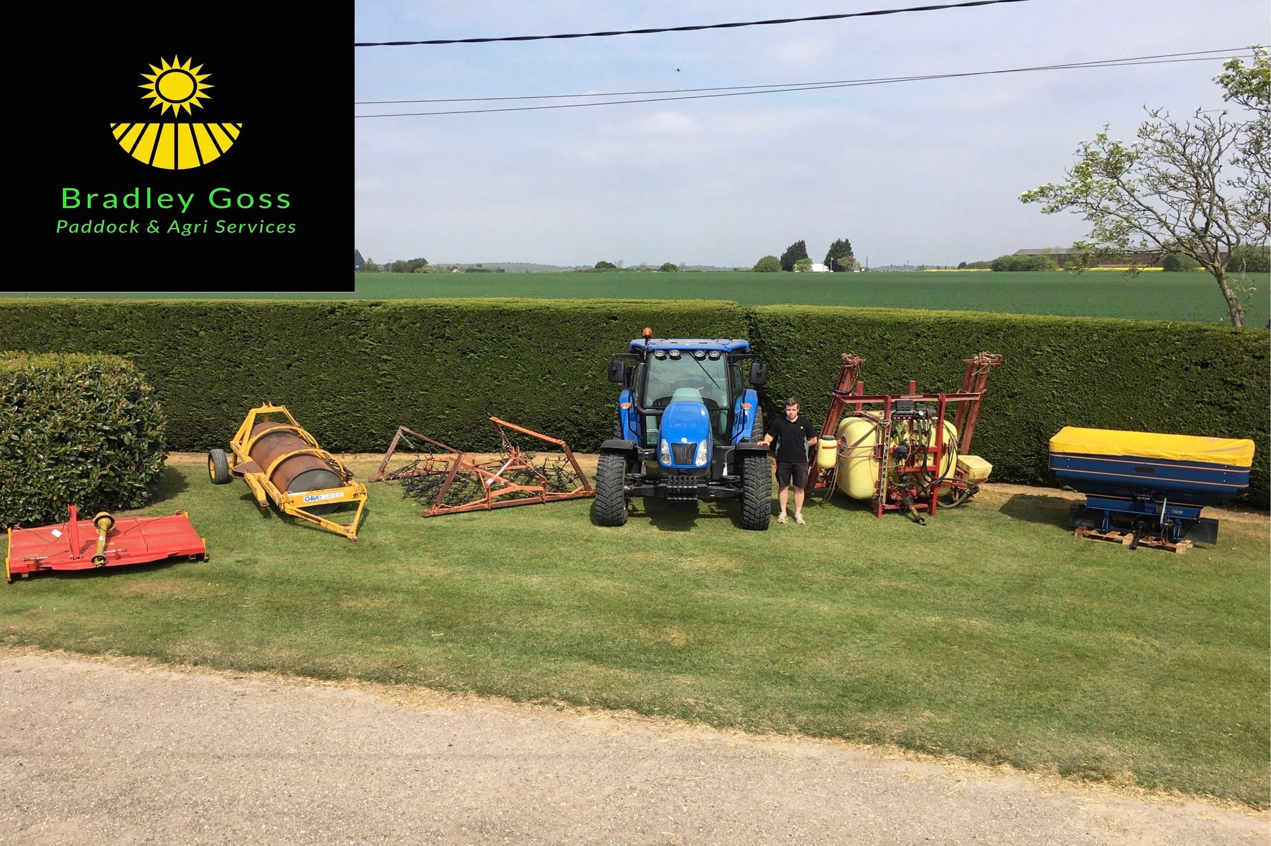 Picture of five tractor implements arranged in a horse shoe shape with tractor and operator in the middle. Set on grass, green conifer hedge behind, bright blue sky. Business logo in top left corner