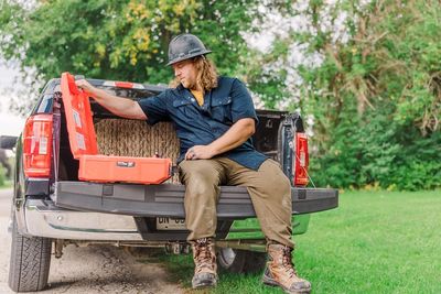 Man sitting on truck tailgate with an open orange case.