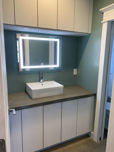 A modern bathroom upgrade with a vessel sink, concrete countertop, and LED-backlit mirror.