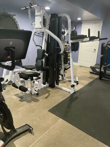 A custom home gym installation with strength equipment, cardio machines, and rubber flooring.