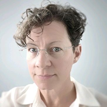 Portrait of a person with glasses and curly hair.