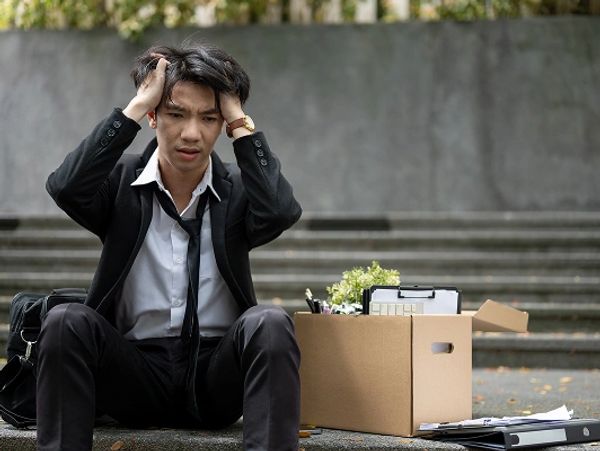 frustrated-asian-businessman-sits-stairs-with-box-after-getting-fired