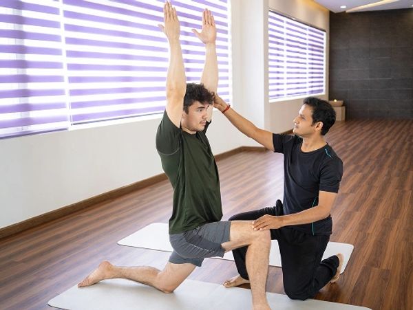 serious-indian-instructor-helping-beginner-yoga-class