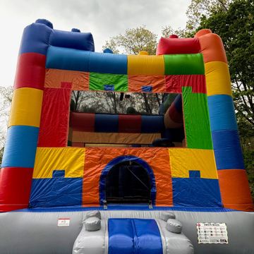 Colorful inflatable bounce house set outdoors under cloudy sky.