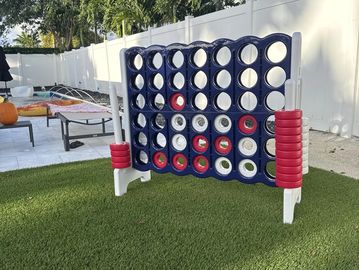 Outdoor giant Connect Four game set on grass with red and white discs.
