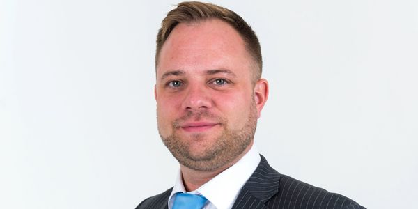 Professional man in a pinstripe suit and blue tie smiling.