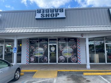 Barbershop storefront with promotional images and services listed on windows.