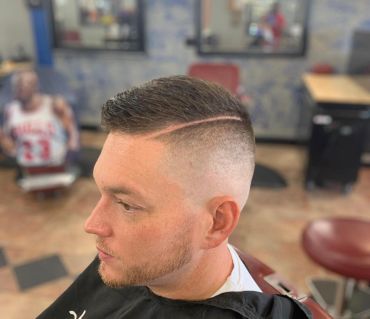 Side view of a man with a fresh fade haircut and a hard part line.