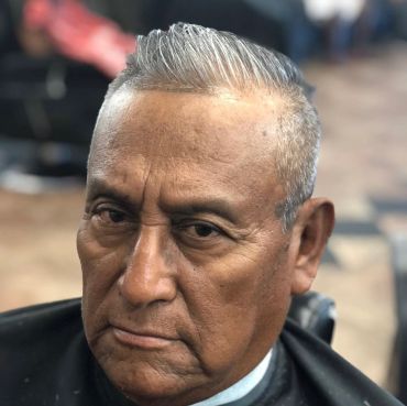 Close-up portrait of an elderly man with a serious expression and grey hair.