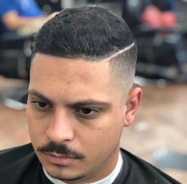 Man with a fresh fade haircut and a shaved line part.