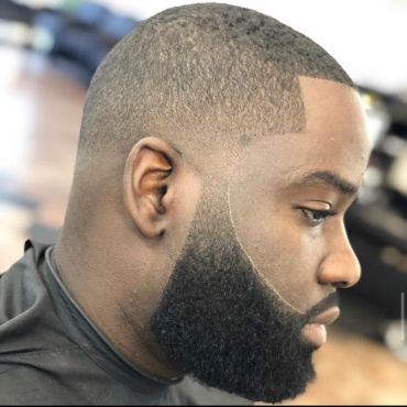 Side profile of a man with a clean, sharp haircut and well-groomed beard.